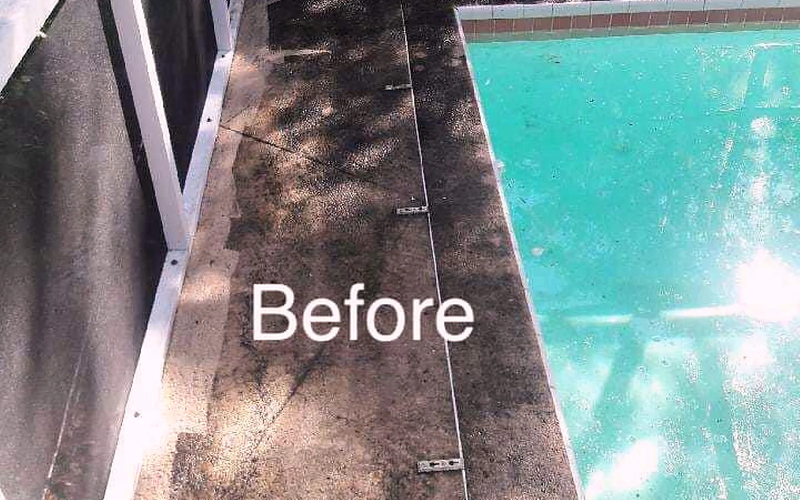Pool deck with dark buildup around a screened pool before exterior cleaning.