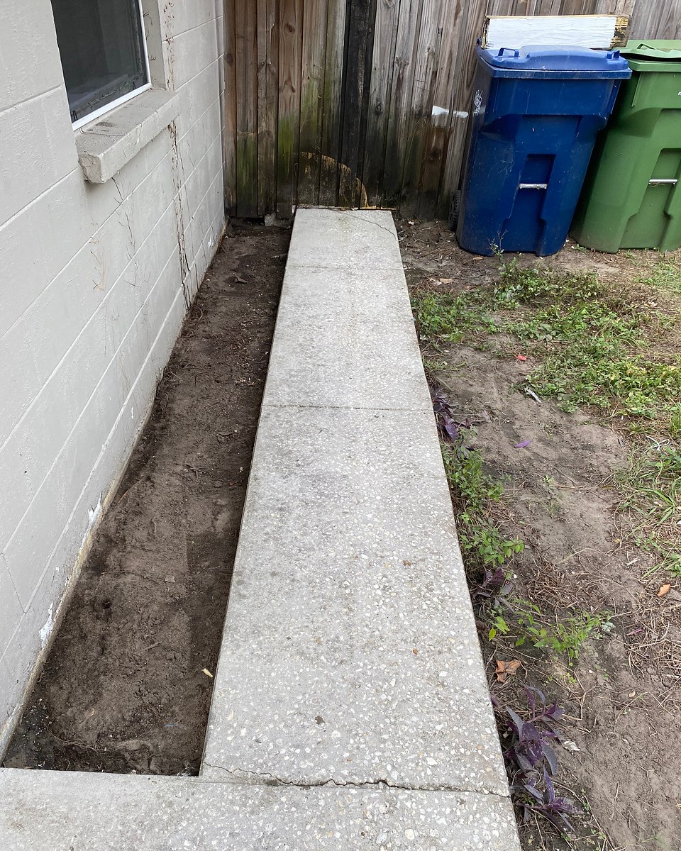 The same concrete walkway after cleaning, showing a lighter exposed-aggregate surface.