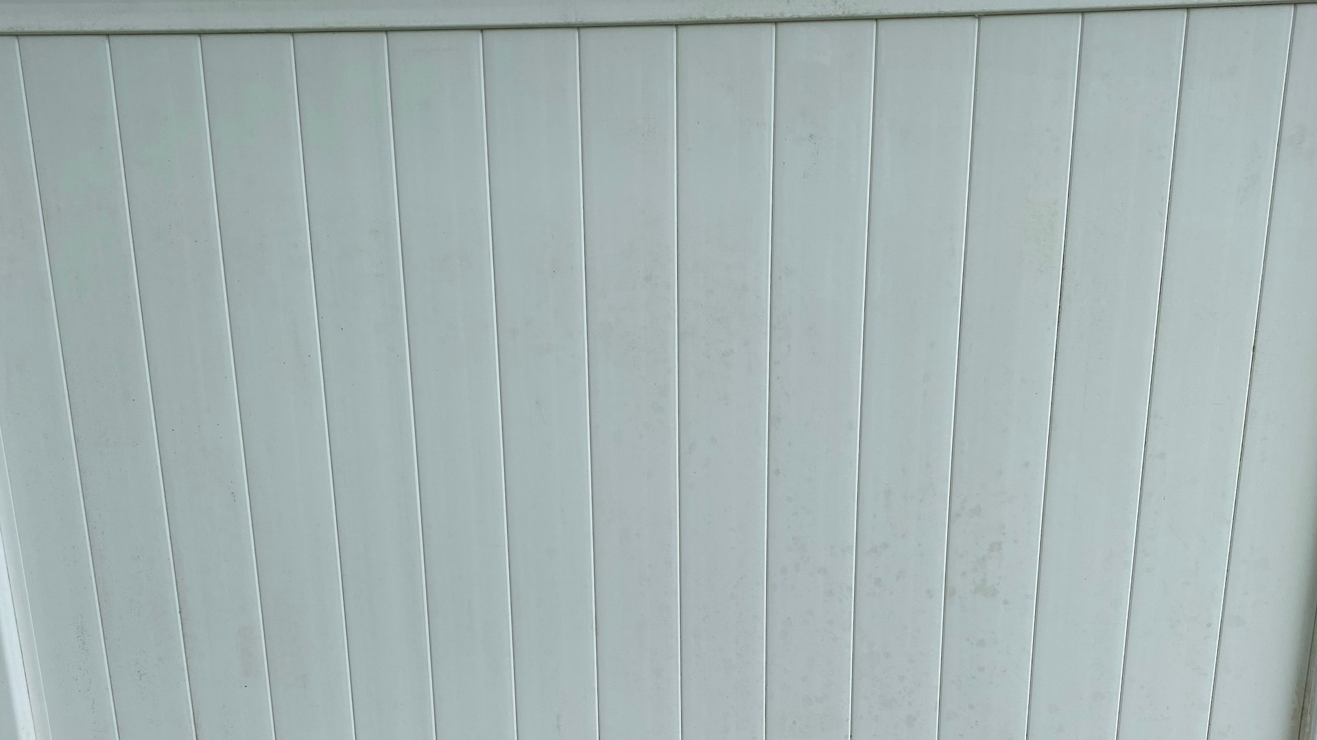 The same white vinyl fence panel after exterior cleaning.