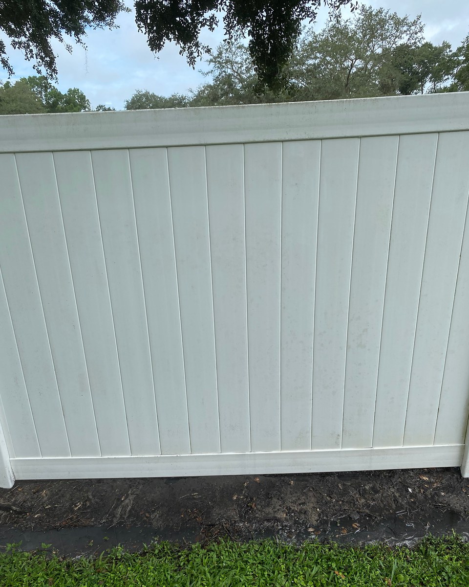 The same vinyl fence panel after cleaning, with the lower-edge buildup no longer visible.